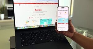 Una mano sosteniendo un teléfono frente a una computadora portátil